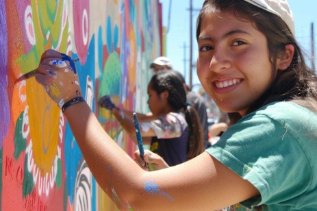 Grupo de adolescentes y jovenes realizan actividades juntos como pintar murales