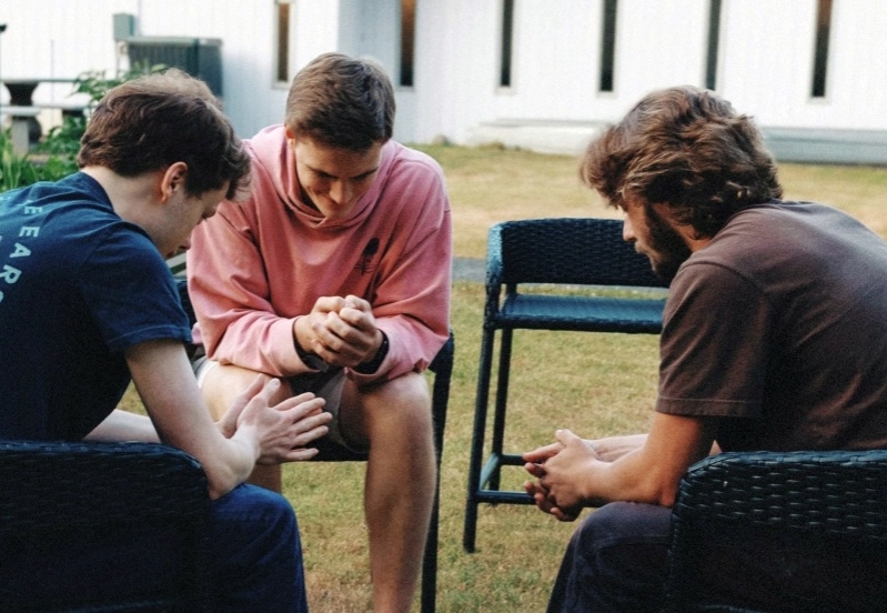 Tres jovenes reunidos orando