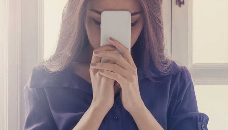 Mujer orando con teléfono en las manos