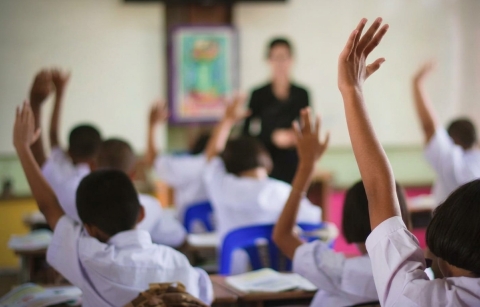 Niños en clase levantando la mano